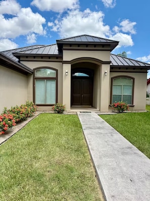 A two-story house with a front entrance, a driveway, and a well-maintained lawn. - The Pinehurst Retreat - 3BR with Golf Course Views (Harlingen)