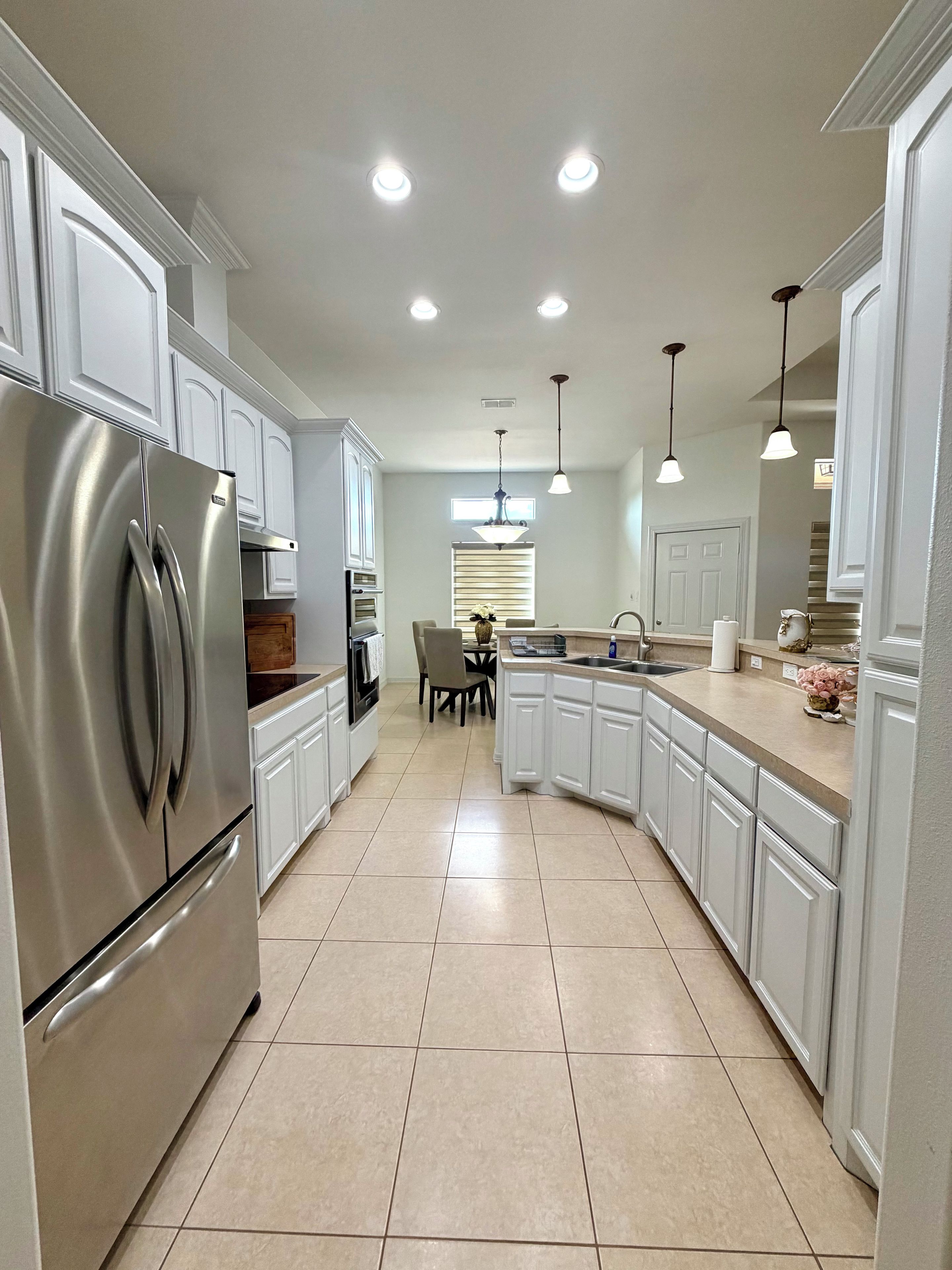 A modern kitchen with white cabinetry, stainless steel appliances, and recessed lighting.