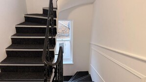 Eine Treppe mit Handlauf, Teppichstufen und einem Fenster mit Blick ins Freie.