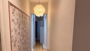 Ein Flur mit floraler Tapete, einer Pendelleuchte und einer Heizkörper.