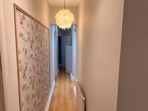 En hall med en blommig tapet, en hängande lampa och ett element.