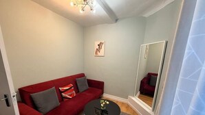 Ein gemütlicher Wohnbereich mit einem roten Sofa, einem kleinen runden Tisch und einem Spiegel.