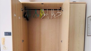 Ein Schrank aus Holz mit Kleiderstange und zwei Schubladen.