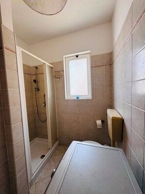 A bathroom with a shower, toilet, and a window. - Fully furnished studio apartment across from Angulo Beach (Santa Maria)