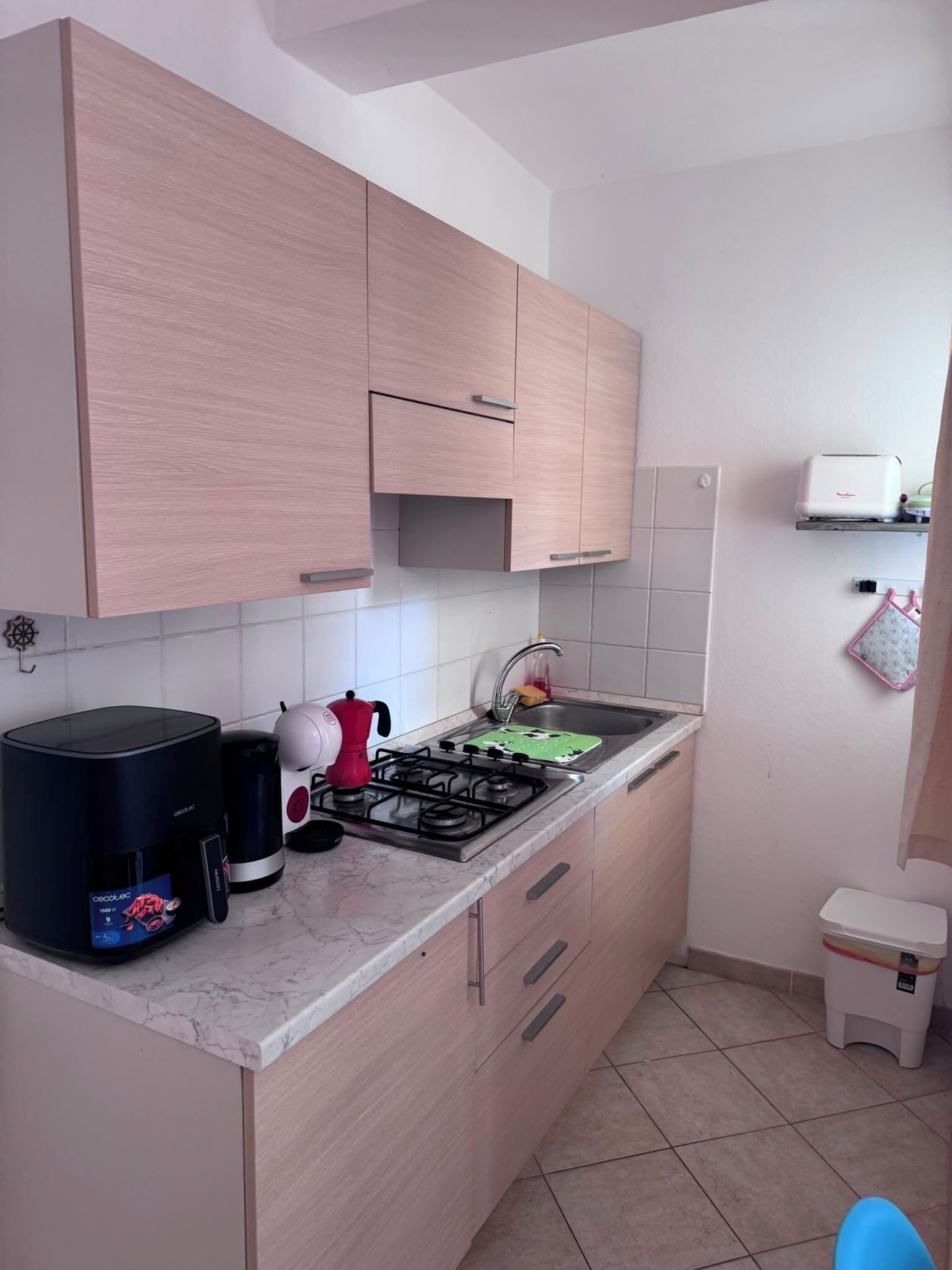 Eine Küche mit hellen Holzschränken, einem Gasherd, einer Kaffeemaschine und einem Toaster.