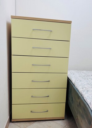 A tall, light-colored dresser with multiple drawers and handles, positioned next to a bed with a patterned bedspread. - Fully furnished studio apartment across from Angulo Beach (Santa Maria)