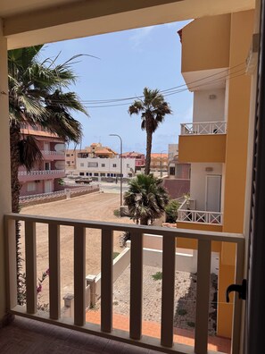 A balcony with a view of a residential area, including houses and a palm tree. - Fully furnished studio apartment across from Angulo Beach (Santa Maria)