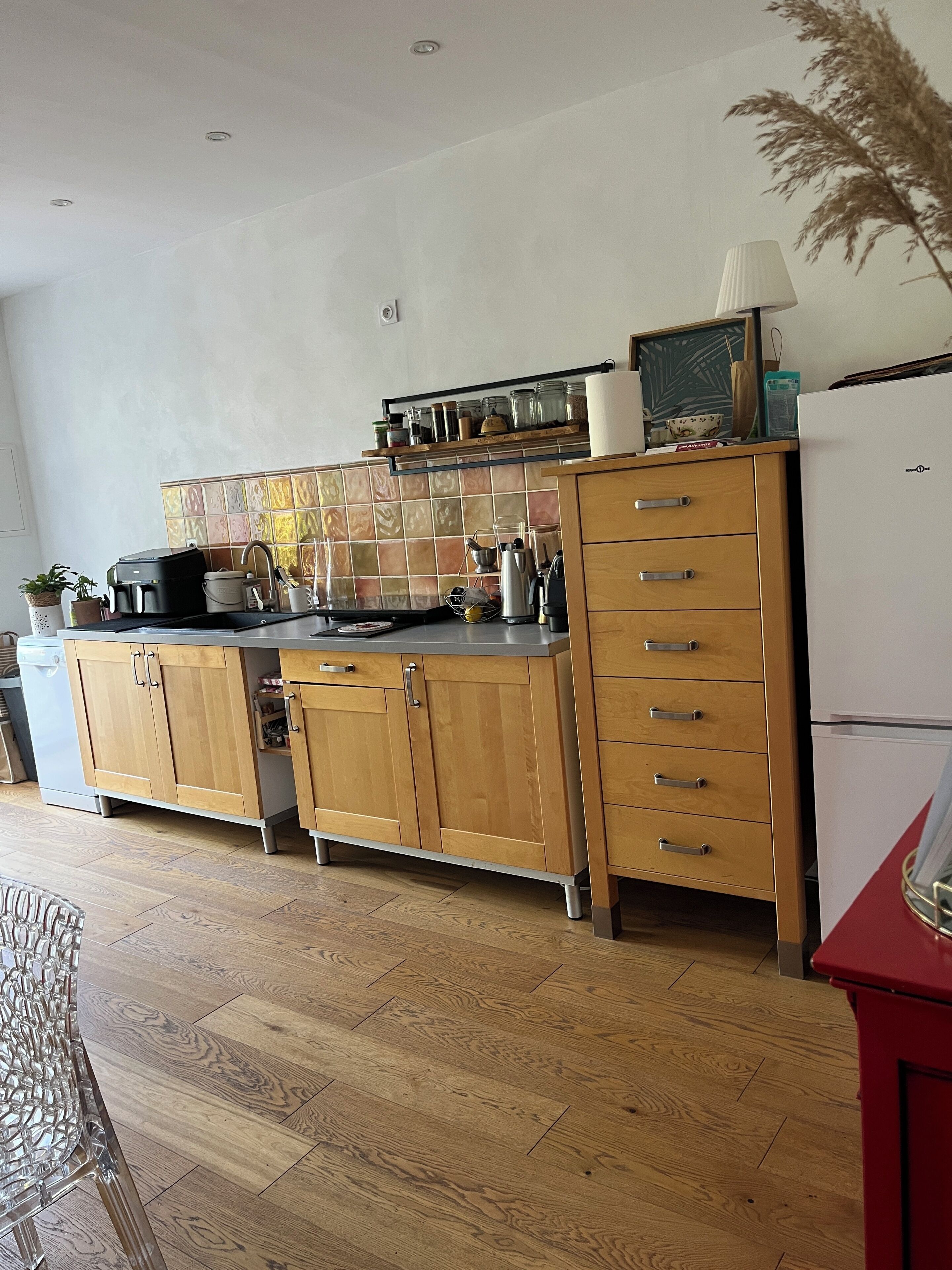 Een keuken met houten kastjes, een aanrecht en een betegelde achterwand.
