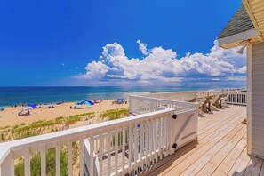 Eine Holzterrasse mit Blick auf Strand und Meer.