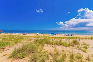 Une plage avec des dunes de sable, des parasols et des gens.