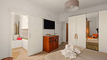 Ein Schlafzimmer mit einem Bett, einem Kleiderschrank, einem Fernseher und einem Spiegel.