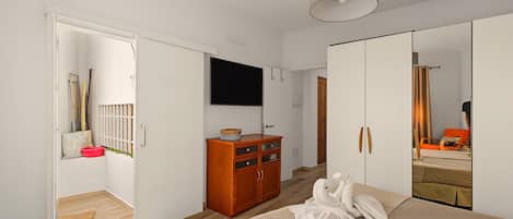 A bedroom with a bed, a wardrobe, a television, and a mirror.