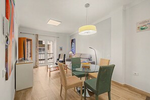 A modern living room with a glass dining table, wicker chairs, a sofa, and a ceiling light fixture. - Vacation Apartment 'Matias Padron House' with Balcony and Wi-Fi (Las Palmas de Gran Canaria)