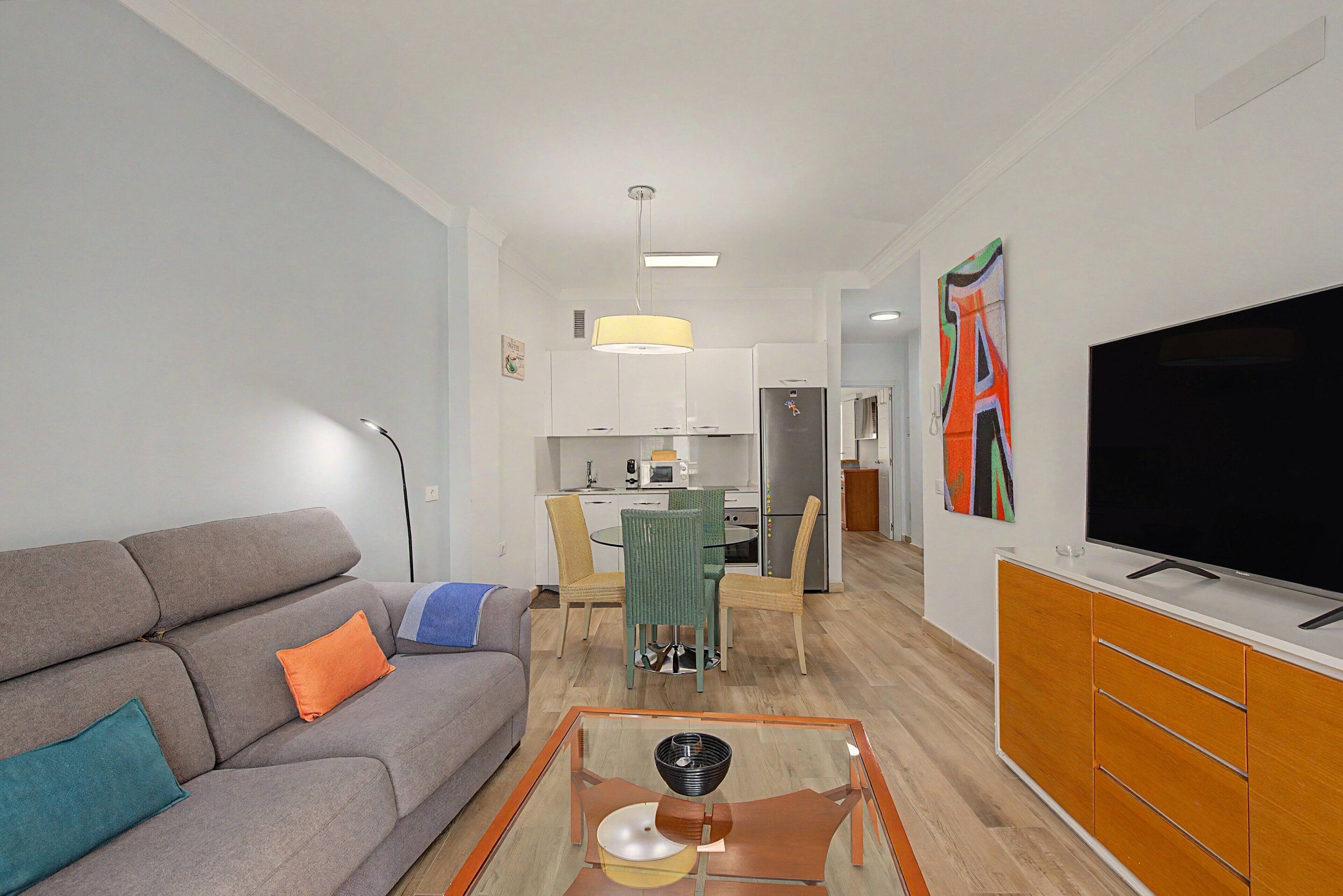 A modern living room with a sofa, a glass coffee table, and a television.