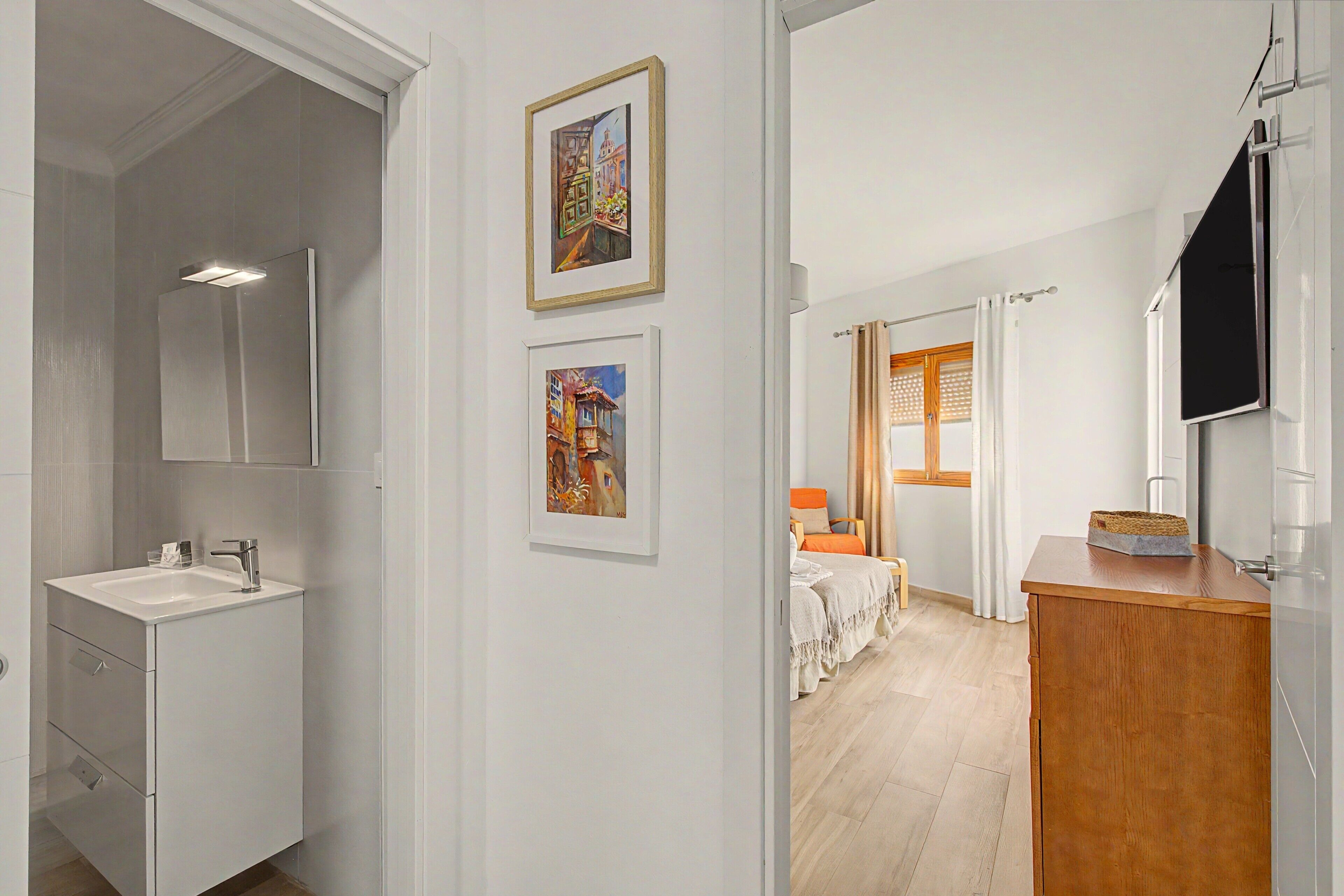 Une salle de bain moderne avec un lavabo, un miroir et une œuvre d’art encadrée accrochée au mur.
