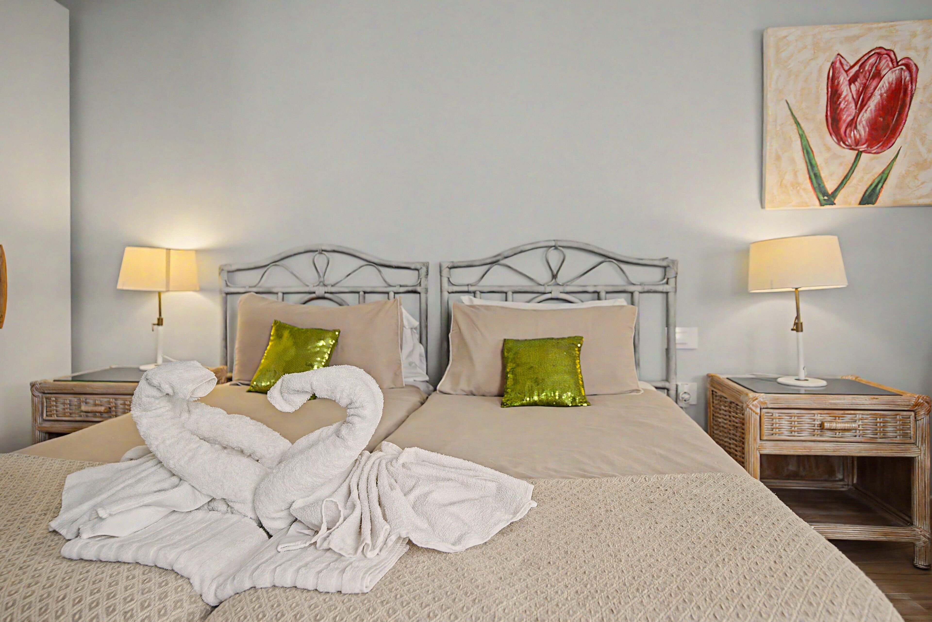 A double bed with two pillows, a decorative towel arrangement, and two bedside tables with lamps.