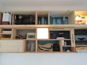 A wooden shelf with various items including a typewriter, books, and decorative objects. - DOMUS ARTIS (Verona)