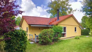 Ein gelbes Haus mit rotem Dach, Schornstein und Veranda.