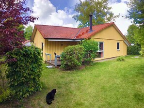 Ein gelbes Haus mit rotem Dach, Schornstein und Veranda.