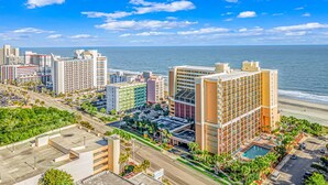 Paisagem costeira urbana com edifícios altos, uma orla marítima e céu azul límpido.