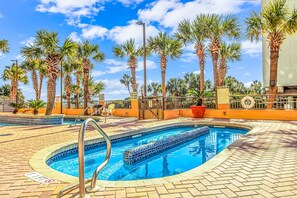 A swimming pool with a circular design, surrounded by palm trees and a brick walkway. - Caravelle 624 Oceanfront Studio (Myrtle Beach)