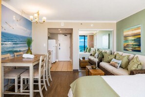 A room with a dining area, a sofa, and a bed. There is a view of the ocean through a window. - Caravelle 624 Oceanfront Studio (Myrtle Beach)