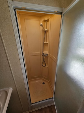 A small, enclosed shower stall with a showerhead, handheld shower, and a drain. - Cabin Sleeps 6 With Pets Welcome (Skegness)