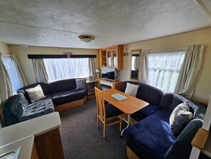 A compact RV interior with a kitchenette, a dining table, and two couches. - Cabin Sleeps 6 With Pets Welcome (Skegness)
