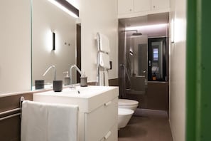 Ein modernes Badezimmer mit einem weißen Waschtisch, einem Spiegel, einer Toilette und einer Duschkabine.