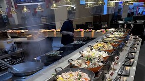 A buffet with various seafood dishes, including clams and mushrooms, and a person in the background. - Vinhomes Skylake Apartment - Layia Homes (Hanoi)