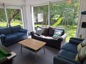 Ein Wohnzimmer mit zwei Sofas, einem Couchtisch und Blick auf eine grüne Außenanlage.