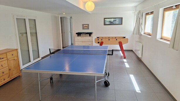 Et værelse med et ping pong-bord, et træskab, en radiator og et vindue med gardiner.