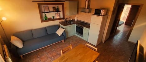 A compact kitchen with a dining area, a sofa, and a small table.