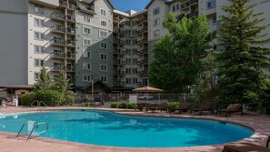 A swimming pool surrounded by a fence, with a multi-story building in the background. - Experience the Ultimate Family Getaway at Sheraton Mountain Vista's 2-Bd Lockoff (Avon)