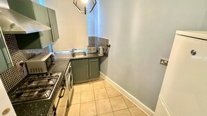 Cocina compacta con estufa a gas, lavadora, pileta y refrigerador.