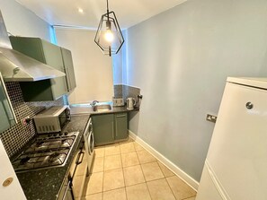 A compact kitchen with a gas stove, a washing machine, a sink, and a refrigerator. - South London, Perfectly Placed (London)