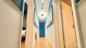 Un pasillo estrecho con suelo de madera, paredes blancas y detalles azules.