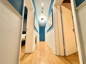 A narrow hallway with wooden flooring, white walls, and blue accents. - South London, Perfectly Placed (London)