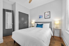 Ein Schlafzimmer mit einem großen Bett, zwei Nachttischlampen, einem Nachttisch, einer Tür und einem Wandbild.