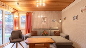 Uma sala de estar aconchegante com um sofá, uma mesa de centro de madeira e uma poltrona.