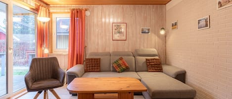 Una sala de estar acogedora con un sofá, una mesa de centro de madera y un sillón.
