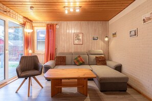 Ein gemütliches Wohnzimmer mit einer Couch, einem Holztisch und einem Sessel.