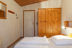 Ein Zimmer mit einem Bett, einem Holzschrank, einer Tür und einem Spiegel an der Wand.