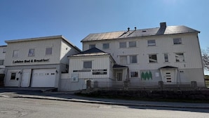 A two-story building with a sign for 'Lofoten Bed & Breakfast' and a smaller attached structure. - Lofoten Bed & Breakfast (Moskenes)