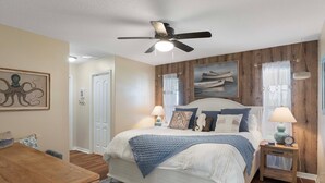Ein Schlafzimmer mit einem Bett, Nachttischen, einem Deckenventilator und einer Holzvertäfelung.