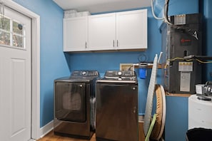 A laundry room with two front-loading washers, a white cabinet above, and a water heater on the right. - WATERFRONT lakehouse with kayaks and dock, firepit and hot tub. (Crystal River)