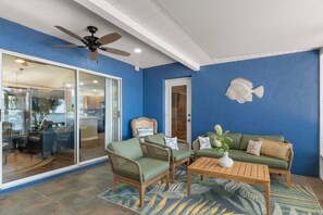 Una habitación con ventilador de techo, decoración de peces en la pared, un sofá y una mesita de café.