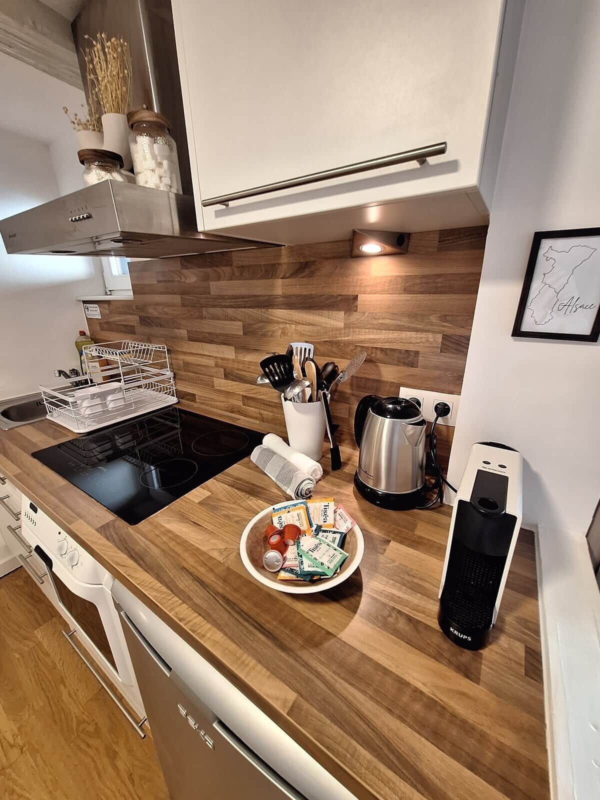 Une cuisine moderne dotée d’un plan de travail en bois, d’appareils électroménagers en acier inoxydable et d’une machine à café.