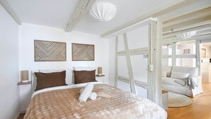 A bedroom with a bed, two wall-mounted lamps, and a wooden ladder. - To complete (Strasbourg)