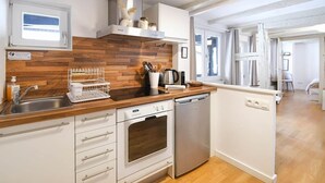 A modern kitchen with a wooden backsplash, stainless steel appliances, and a window overlooking the living area. - To complete (Strasbourg)